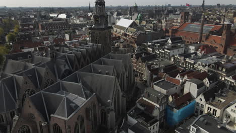 top view of a street going by the old church and the apartments of amsterdam city during sunny day beside a canal in the netherlands