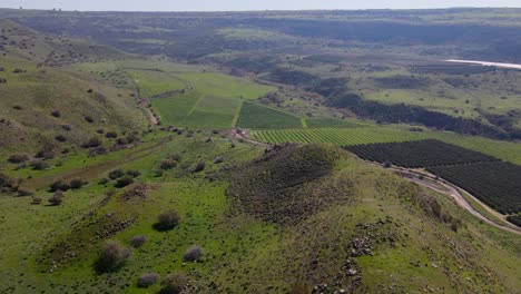 Panning-drone-aerial-view-over-mountain-revealing-farmlands-and-crops,-Israel