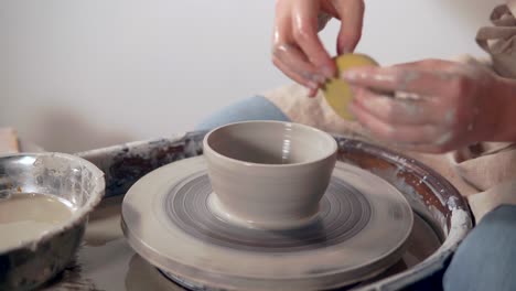 mujer formando un cuenco en una rueda de cerámica