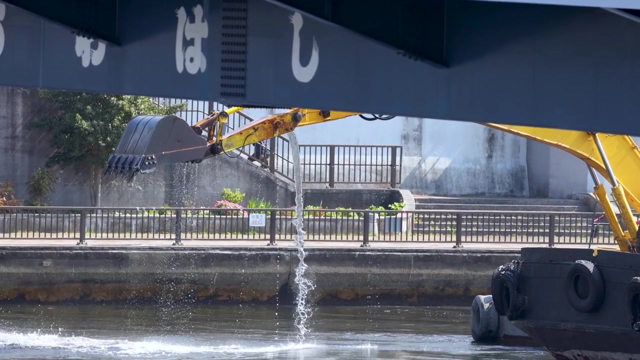 Escavatore giallo che solleva materiale dragato dal fiume