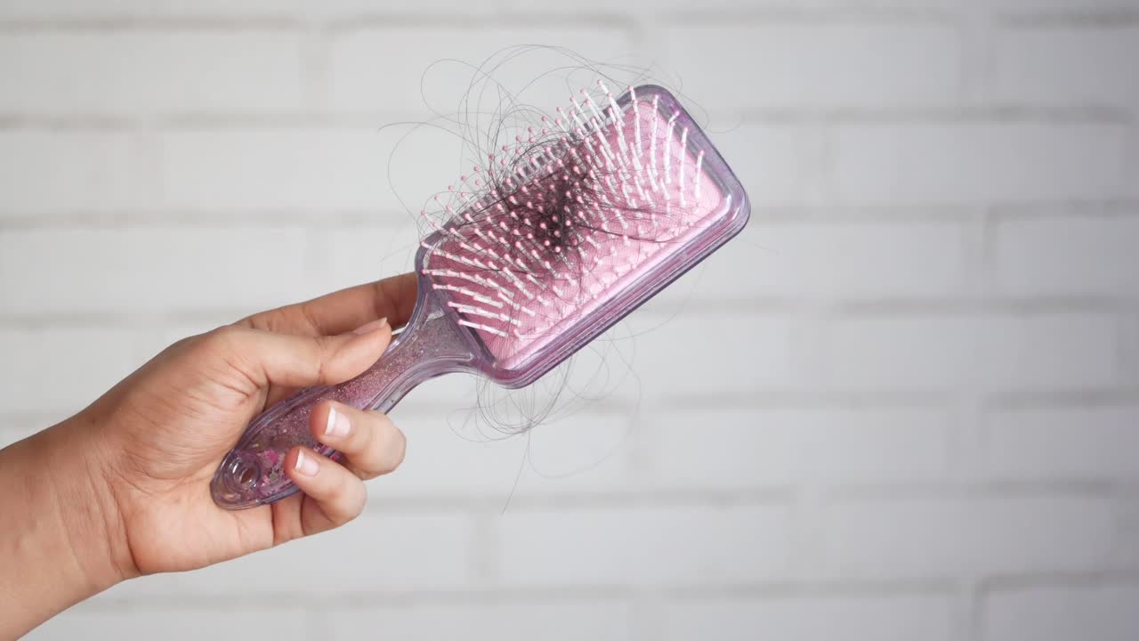 mano con un cepillo para el cabello con pérdida de cabello