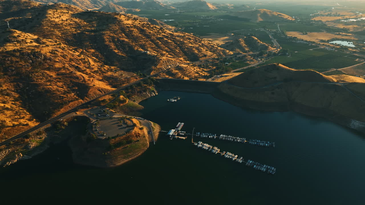 Beautiful lake with dock for yachts and boats surrounded by mountains in California. Lovely green valleys behind the rocks at backdrop.