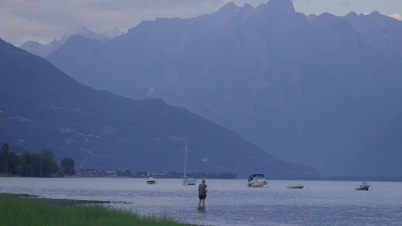 Pesca sul Lago di Como al mattino in acque basse, Italia, regione Lombardia, skyline de La Corvegia
