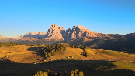 Mountains,-forest-and-grass-fields-with-wooden-cabins-filmed-at-Alpe-di-Siusi-inEuropean-Alps,-Italian-Dolomites-filmed-in-vibrant-colors-at-sunset