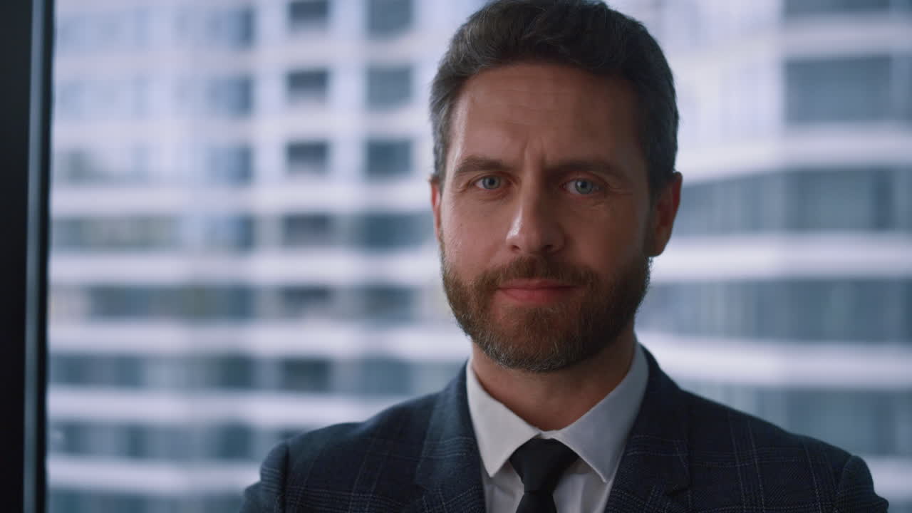 hombre de negocios exitoso mirando a la cámara sonriendo posando en la oficina de la ventana de la compañía.