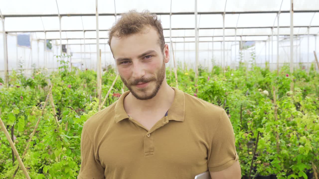 온실에서 카메라를 바라보며 미소 짓는 정원사.