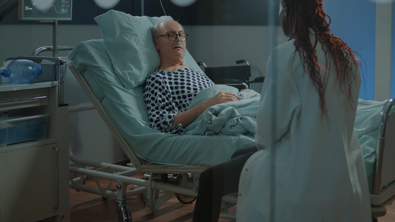 African american doctor talking to sick patient in hospital ward