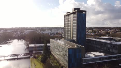 Aerial-view-Pilkington's-glass-head-office,-Shimmering-lake-and-blue-high-rise-with-shared-office-space