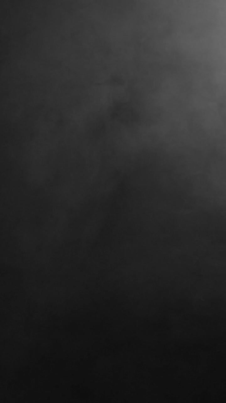 A dark, uniform fog or smoke texture with very subtle movement. A minimal and moody vertical background for compositing or atmospheric scenes