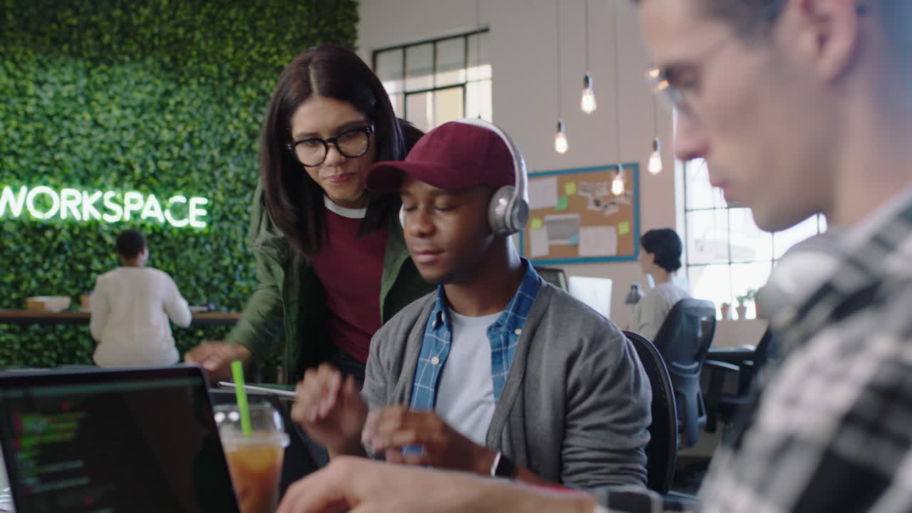 joven ingeniero afroamericano que usa computadora portátil digital software de codificación líder de equipo caucásico mujer que comparte ideas de diseño para el proyecto de aplicaciones de comunicación colegas que colaboran en la oficina