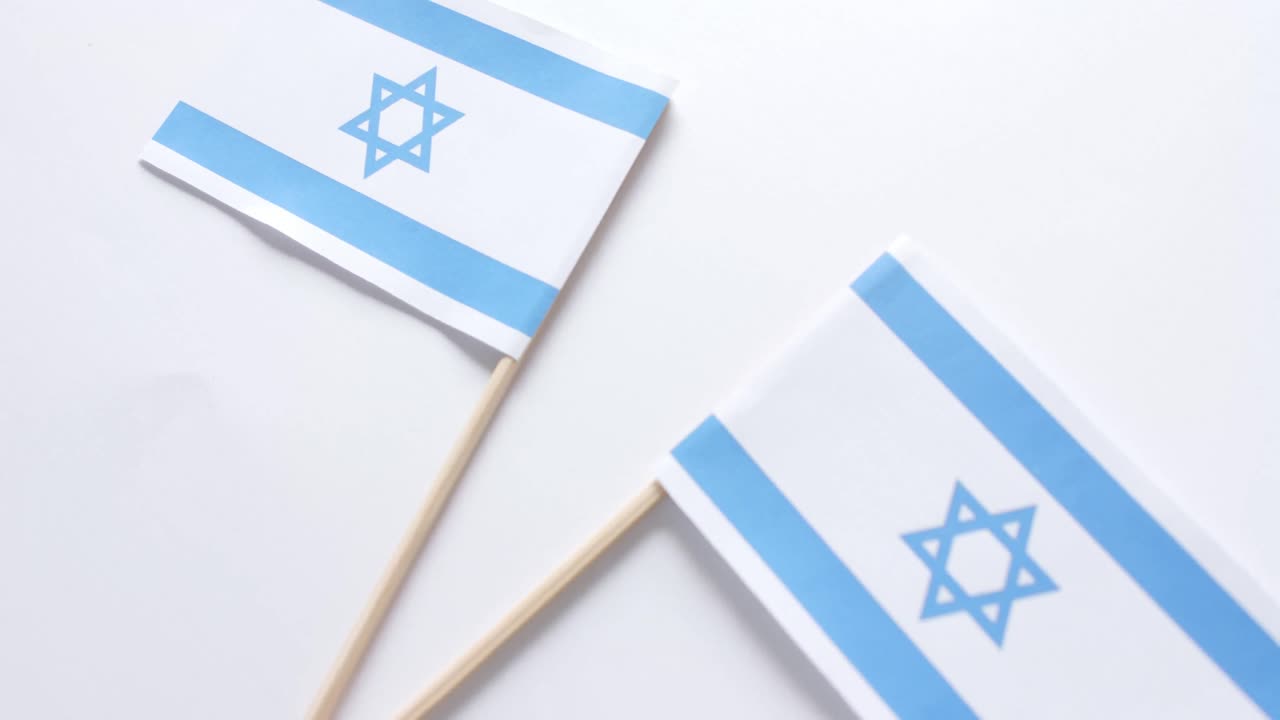 Primo piano di due bandiere di Israele adagiate su sfondo bianco.