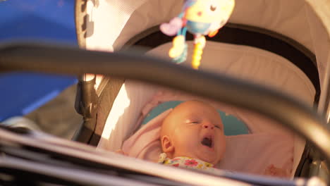 Baby-of-three-months-in-pram-outdoor-on-summer-sunny-day