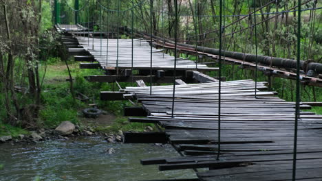 old broken wooden bridge with missing laths over a river in the forest