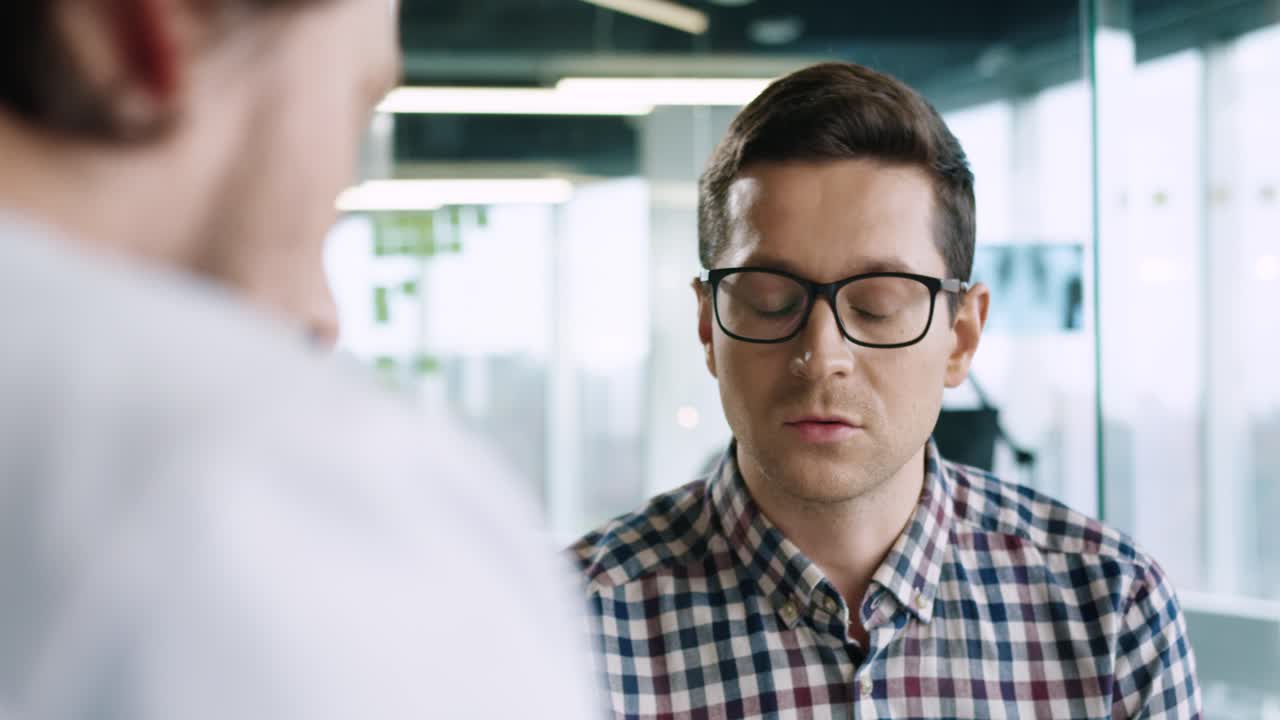 Rear view of caucasian male doctor sitting at desk explaining to male patient treatment for coronavirus in medical consultation