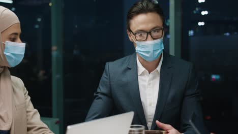 close up view of multiethnic business people group in medical masks in a team meeting in modern office and discussing about a project