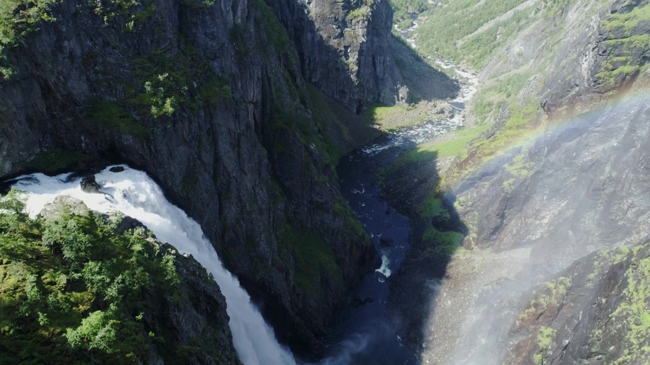 Voringfossen plunges through Norway canyon as sunlight creates rainbow in mist