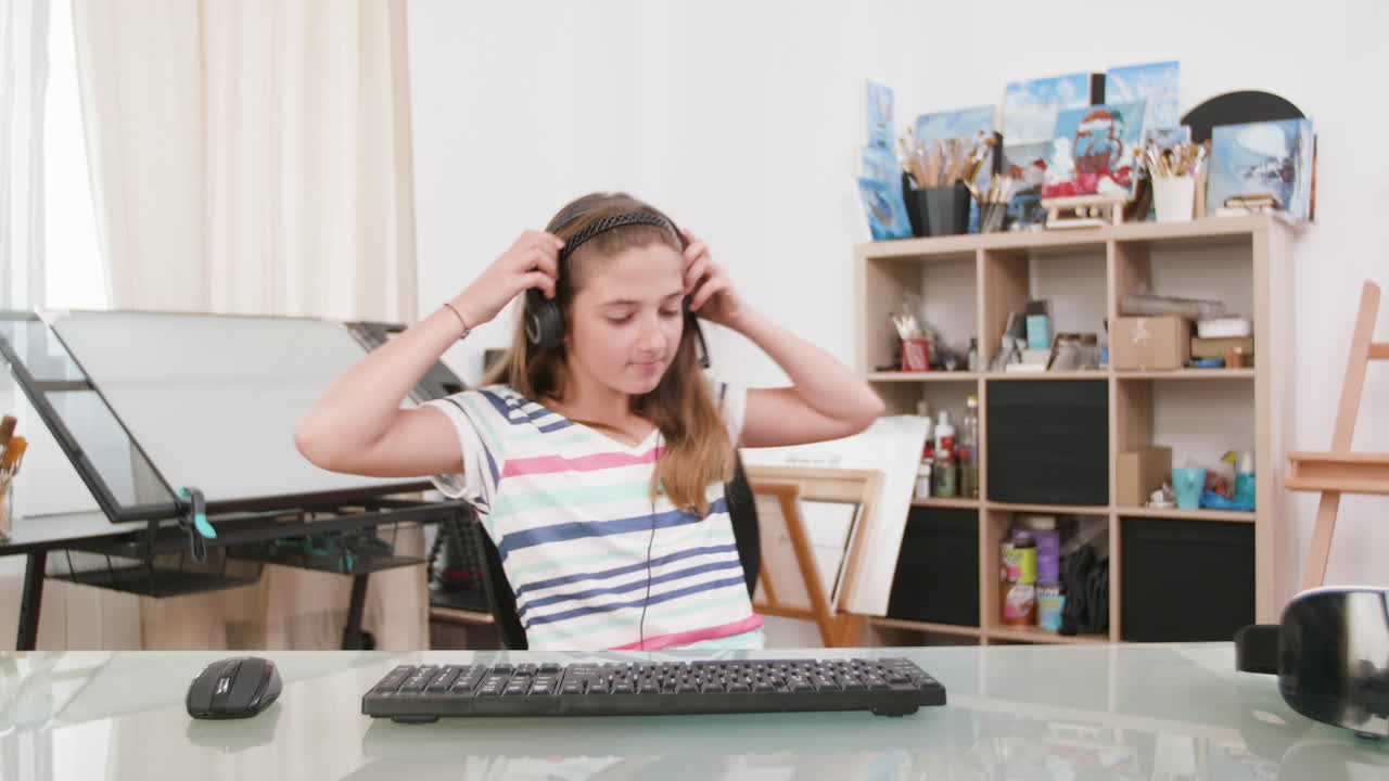 Ragazza adolescente con cuffie che usa un computer a una scrivania