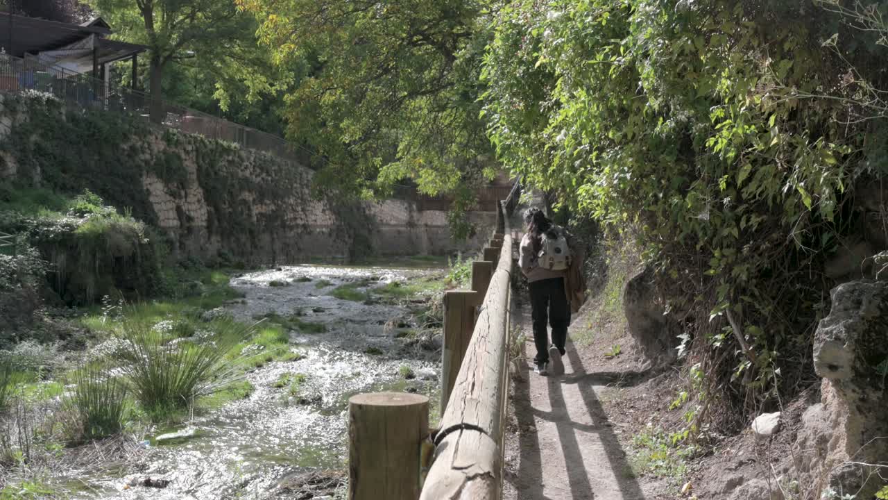 Young brunette girl in brown and black clothing walking near a river in Nerpio