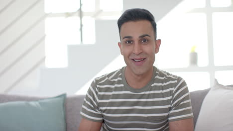 happy surprised biracial man having video call and opening present in sunny living room, slow motion