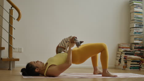 young asiatic woman practicing yoga daily exercises at home lifting her cat with abdominal healthy lifestyle