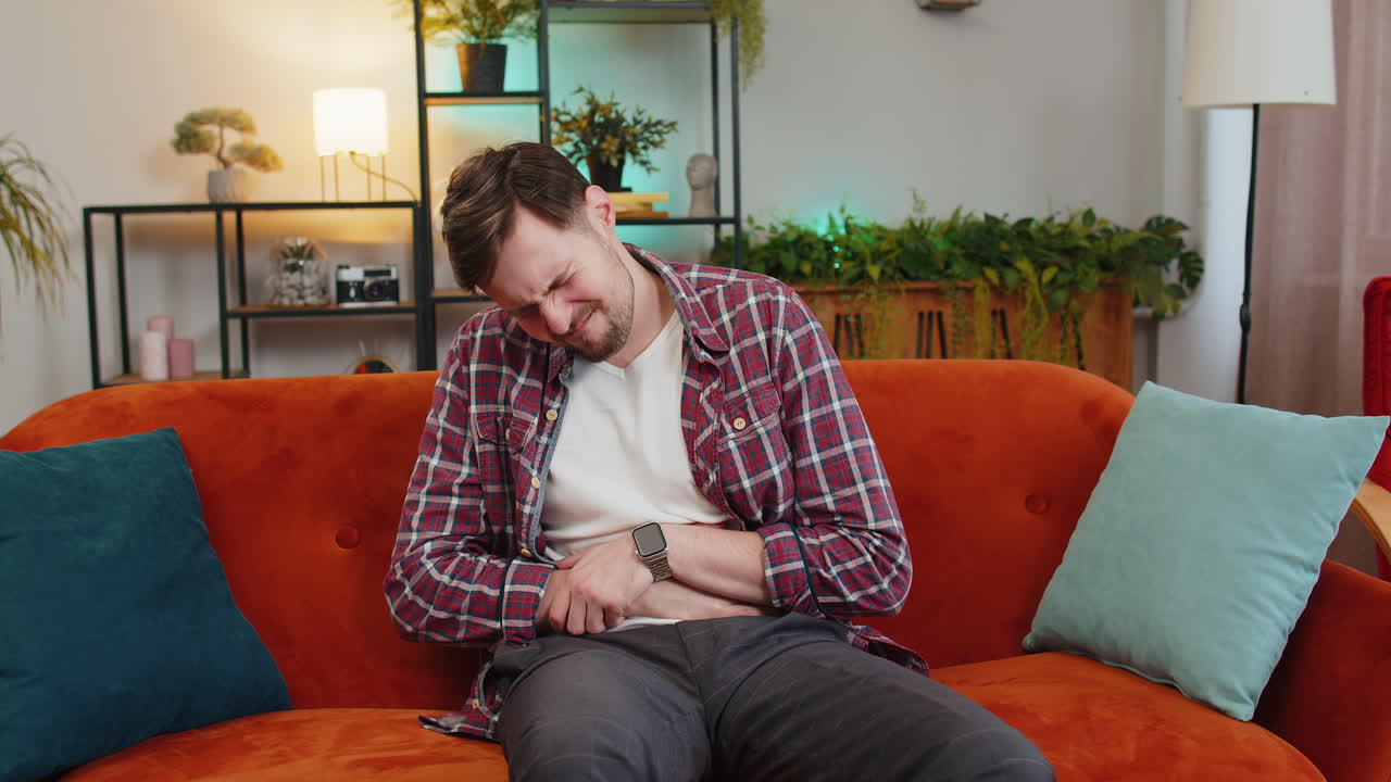 Man lying on sofa feeling sudden strong abdominal stomach ache gastritis problem poisoning diarrhea