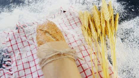 baguette wrapped in paper, wheat grains and flour