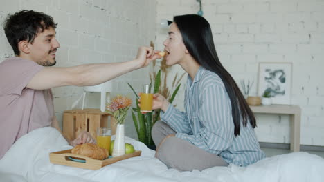 pareja disfrutando del desayuno en la cama