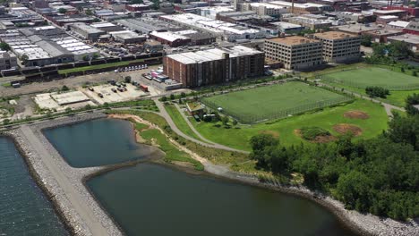 high-up-dolly-shot-towards-soccer---baseball-field-over-the-waters---stone-jetty-on-a-clear-sunny-day-in-Upper-New-York-Bay-in-Brooklyn