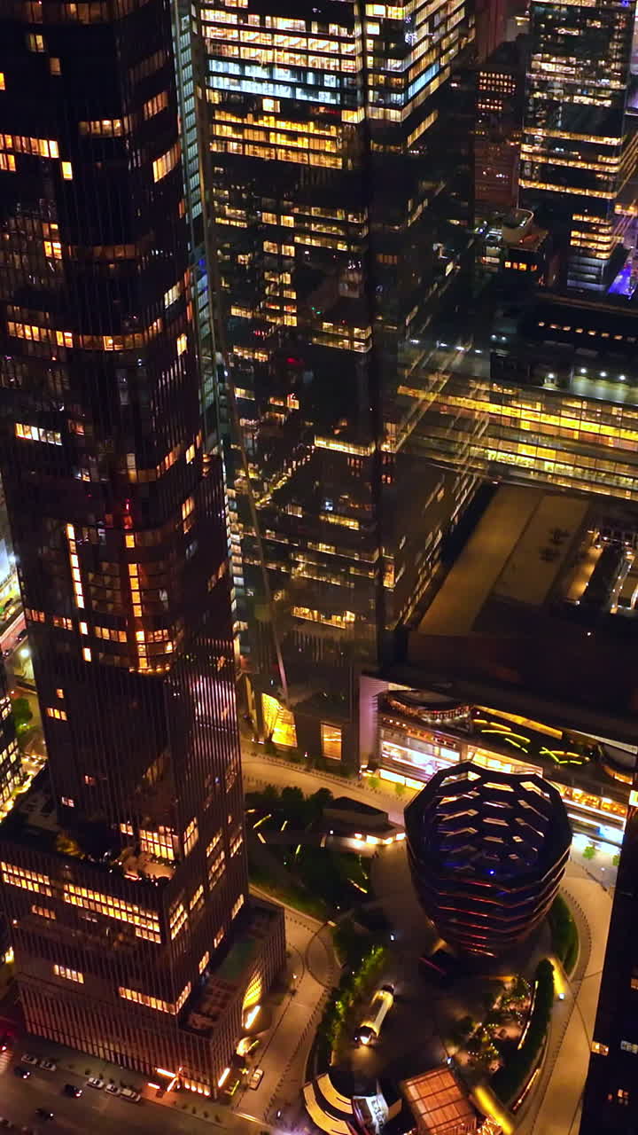 Broad light streets among the skyscrapers of New York. Drone rising along the shining glamorous buildings. Vertical video