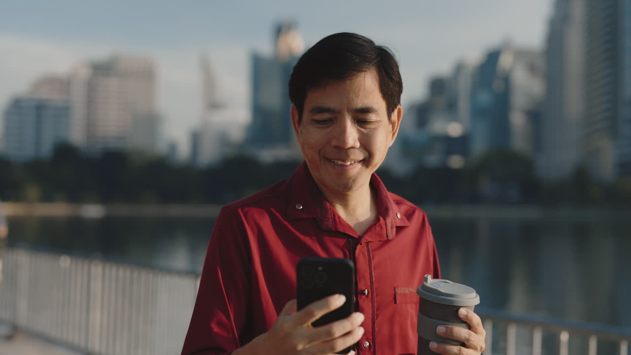 Man using smartphone with coffee outdoors in a city