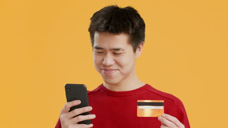 young man using mobile phone and credit card for online payment