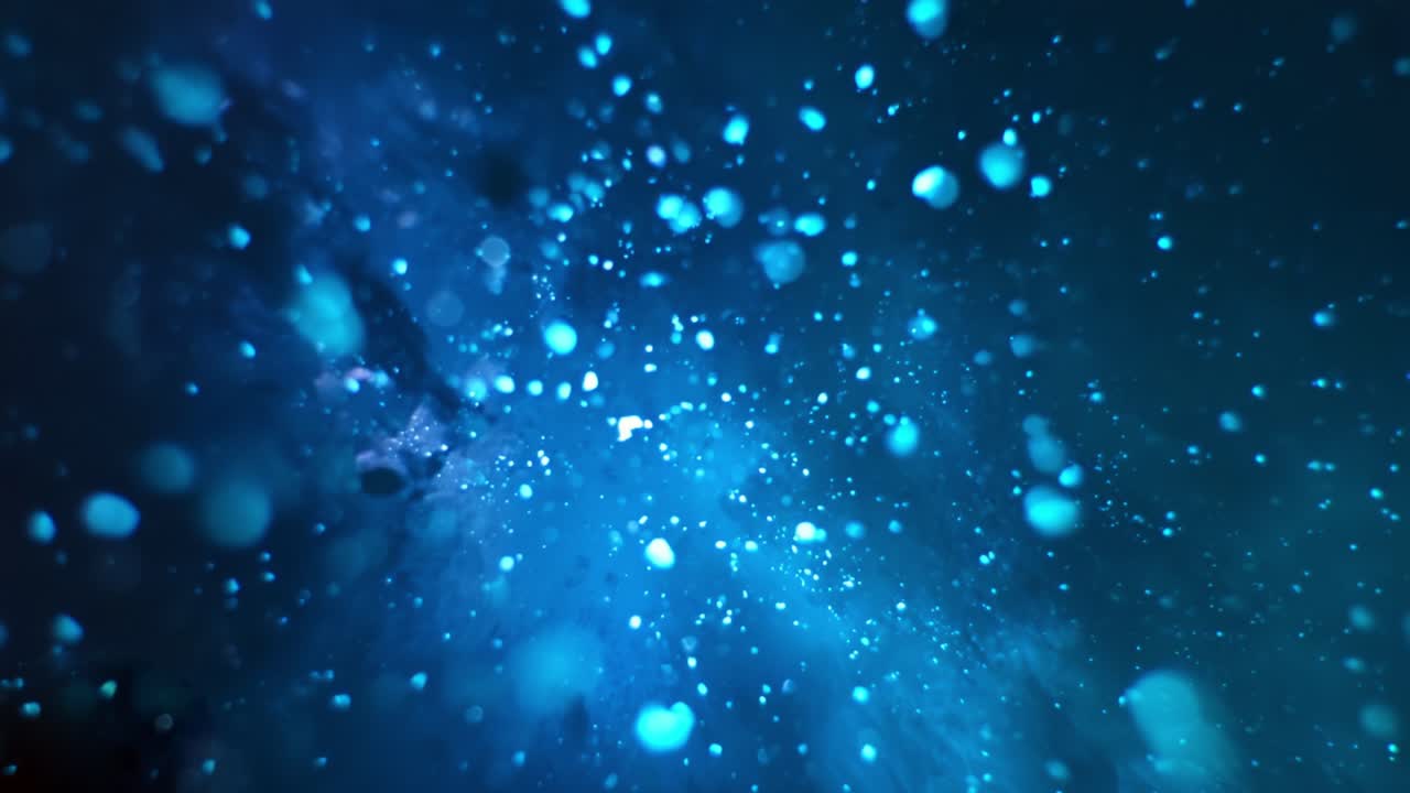 A mesmerizing visualization of shimmering particles swirling through a deep blue cosmic environment, showcasing vibrant hues and ethereal beauty that captivates the viewer's imagination