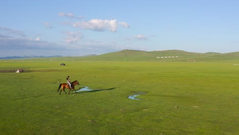 Horsewoman-riding-horse-through-vast-meadow-valley-in-Mongolia