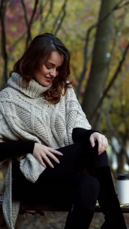Woman with coffee in park. Young woman relaxing with cup of coffee in park Vertical video