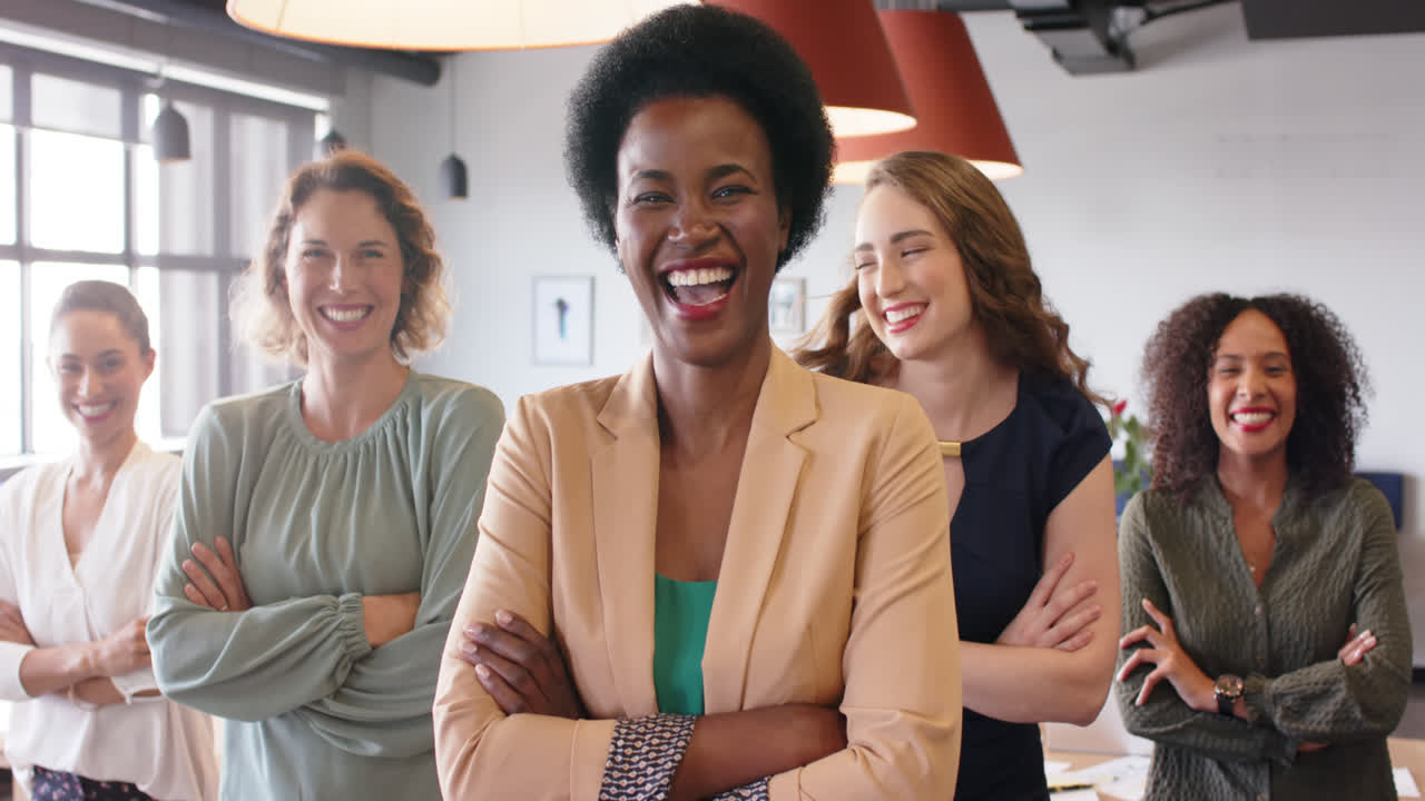 Retrato de empresárias diversas e felizes em pé no escritório com os braços cruzados e sorrindo, em câmera lenta