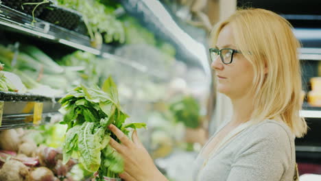 mujer joven elige cuidadosamente lechuga en la tienda estilo de vida saludable y nutrición adecuada