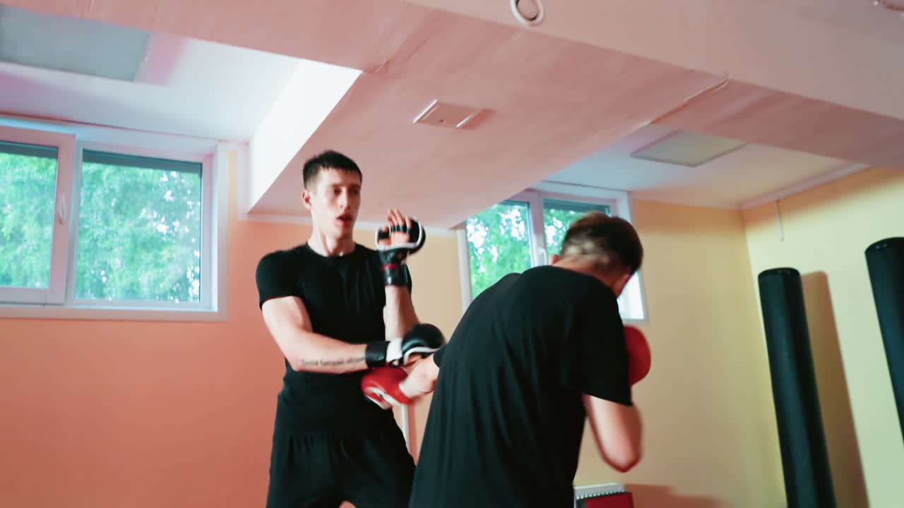Karate practitioners sparring inside dojo, wearing gloves, demonstrating martial arts techniques with focus, strength, while training combat skills, endurance, and precision in practice session