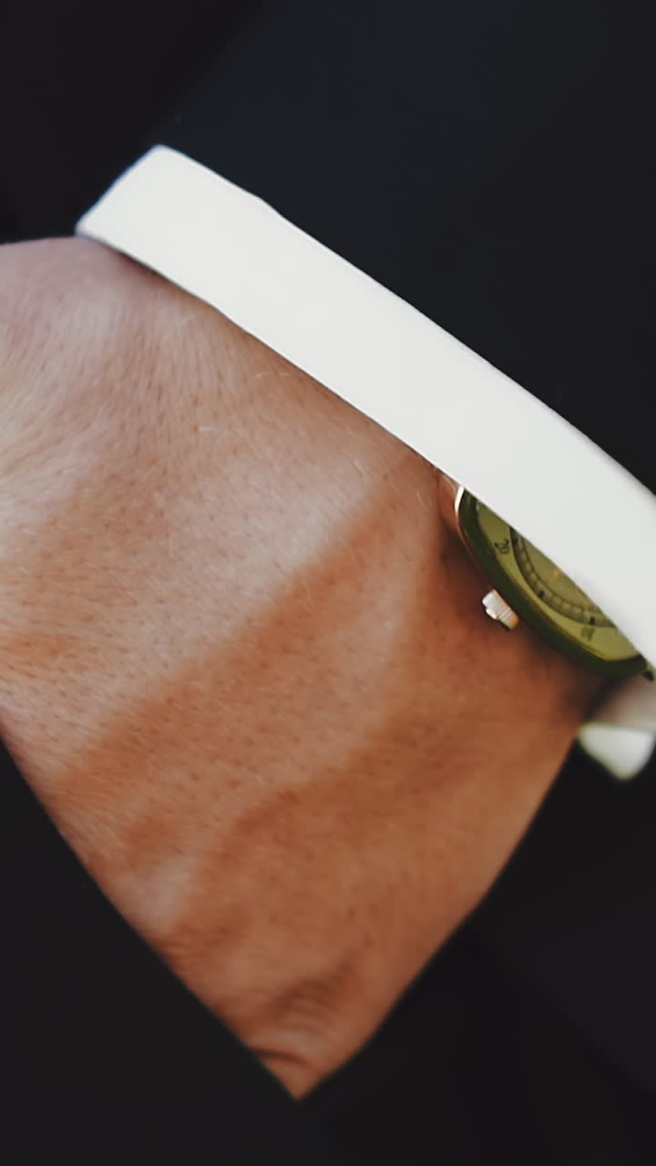 CU, slow motion: confident businessman in trendy dark suit puts hand into pants pocket walking on blurred background in spring park extreme close view