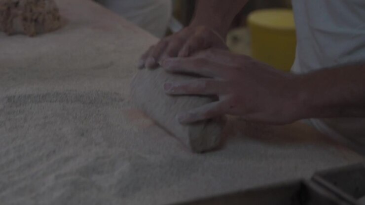 master baker kneads bread and sorts it into baking pans