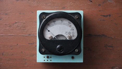 old analog voltmeter with a metal arrow. the voltmeter arrow moves up and down.