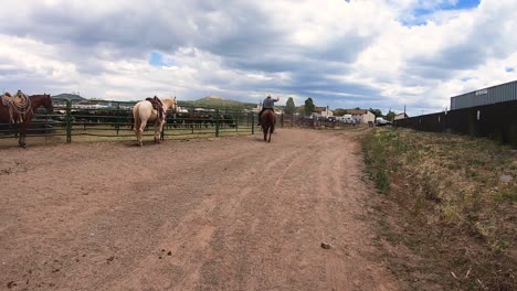 cowboys ride and walk along a dirt road in the rodeo grounds in northern arizona