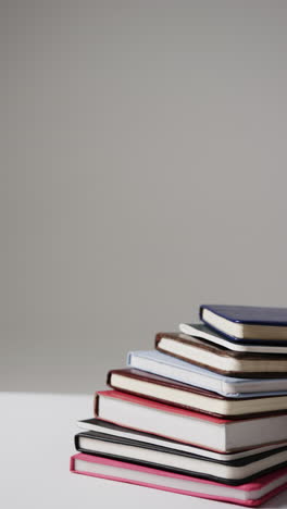 vertical video of stack of books with copy space on grey background, in slow motion