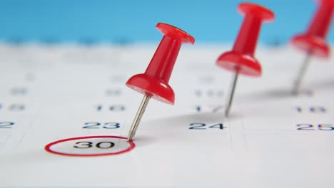 calendar with red push pins marking a date