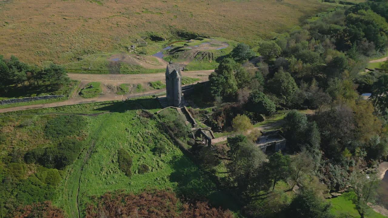 одинокая каменная башня, построенная на склоне холма, окруженная лесом и болотом, с спиральной панелью наружу, раскрывающей больше пейзажа