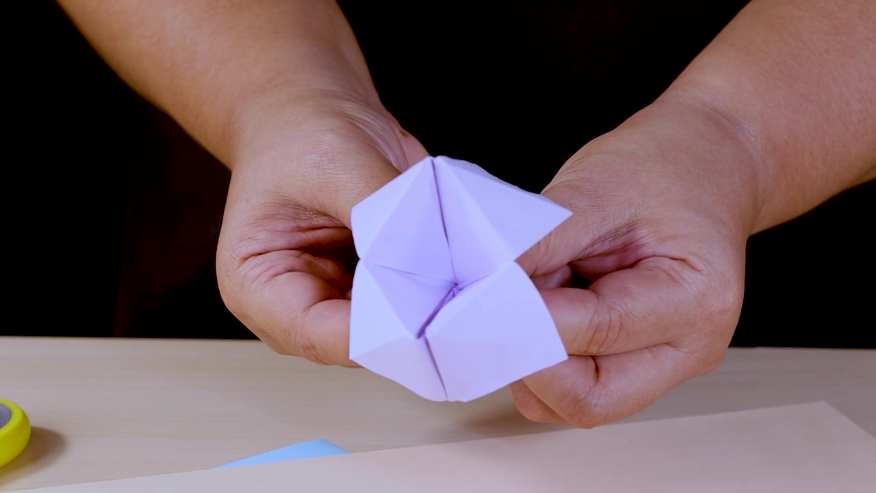 Primo piano di mani che giocano con un indovino di carta viola