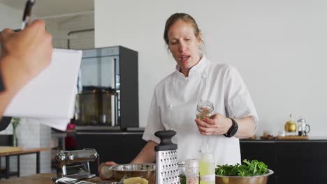 cocinera caucásica vertiendo especias en un plato