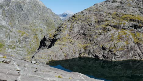 toma panorámica del tranquilo lago natural rodeado de vastas montañas durante el día soleado y el cielo azul