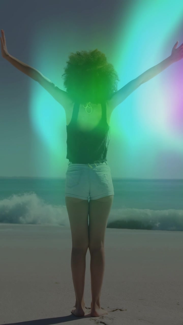 Vídeo vertical: Mulher arrumando o cabelo, levantando os braços na areia enquanto a luz varre, incentivando a alcançar para um anúncio.