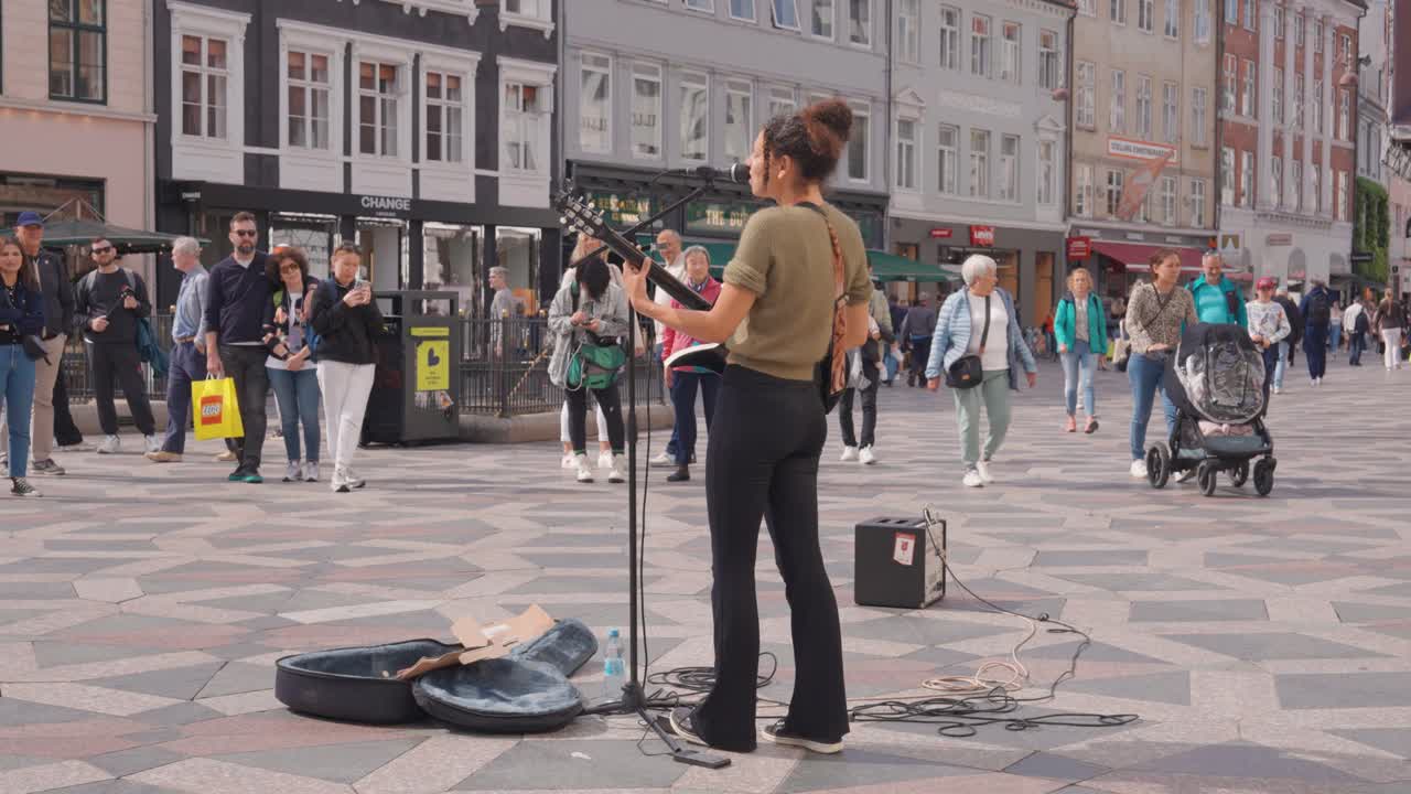 Female singer play guitar and perform on public street of Copenhagen