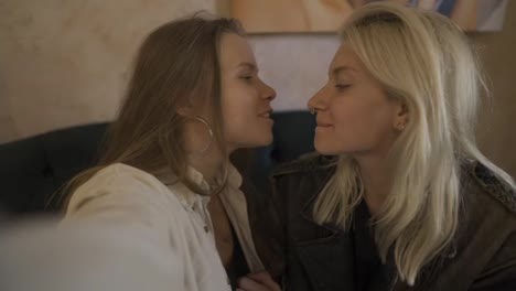 Two-affectionate-women-kissing-sensually-at-the-cafe